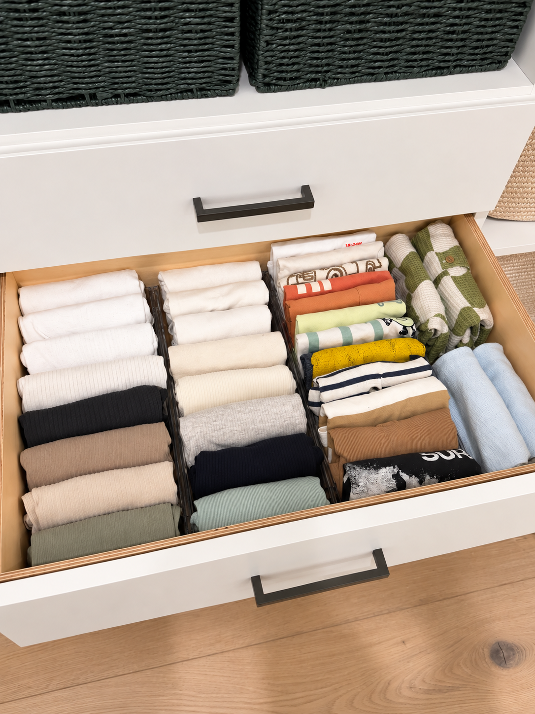 Open closet drawer with neatly file-folded children’s shirts sorted by color